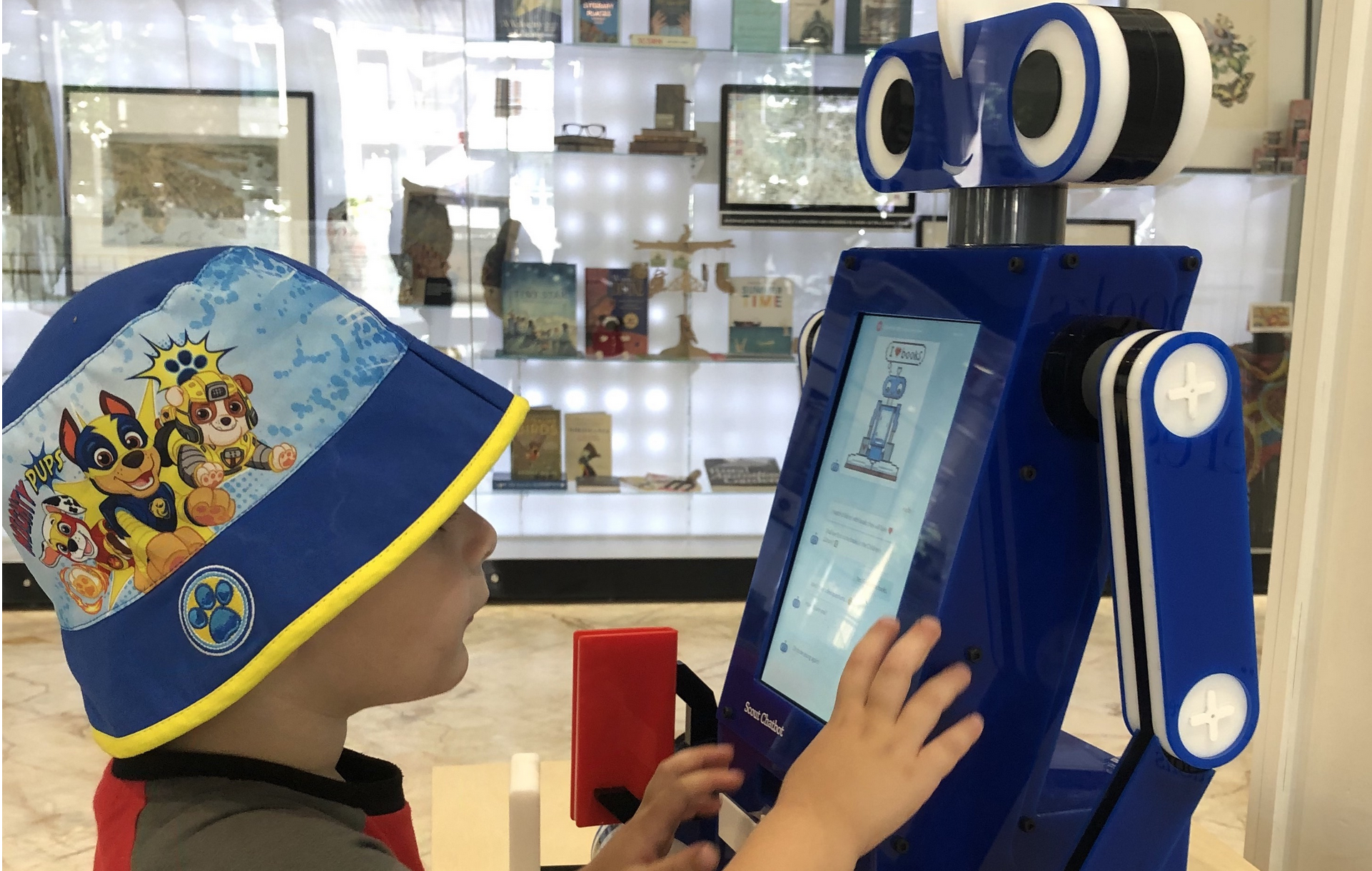 A kid using a Huey the Bookbot kiosk